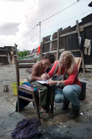 Isidore, la bénévole, aide Baïram à apprendre à écrire